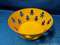 Top view showing yellow enamel bowl with human-shaped cutouts around the sides.