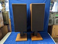 Front view of pair of speakers on stands with black cloth grills attached