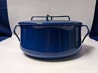 Front view of blue enamel pot with lid in place showing round shape and loop handles