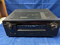 Front and top view of the Denon AVR-591 receiver showing control panel, digital display, source select and volume knobs, and ventilation slots on top.