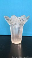 Front view of a clear textured glass vase with ribbed design and scalloped top edge resembling flower petals