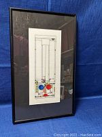 Full view of framed embroidery with geometric design and colored accents