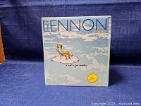 Front view of the John Lennon Anthology box with illustrated cover featuring John Lennon on a cloud.