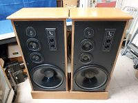 Front view of both speakers with grills removed showing tweeter, midrange drivers, and 15-inch woofers