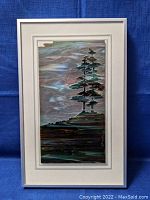 Framed glass art panel showing stylized landscape with trees and rocky land, signed and numbered.