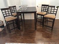Four bar stools arranged around a dining table on hardwood floor
