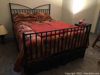Metal-framed bed with mattress, pillows, comforter, and sheets in a room with beige walls.