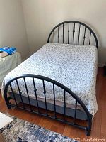 Full view of bed showing metal headboard and footboard with quilt covering mattress