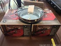 Two boxed sets of Hometrends 3-quart stainless steel chafing dishes with one stainless steel chafing dish with lid placed on top.