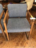 Front view of one upholstered chair with wood frame and gray textured fabric on seat and back.