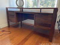 Front angled view of walnut-finished desk showing left two drawers, center keyboard tray space, and single right-side drawer under back lip rail.