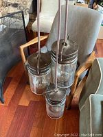 Three pendant lights attached together, hanging, showing metal tops and glass shades.