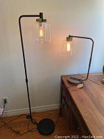 Black metal base floor lamp and bronze metal base table lamp with clear glass shades and filament bulbs