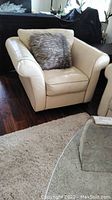 Front view of cream leather armchair with faux fur cushion placed on seat.
