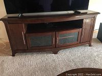 Front view of the media cabinet showing the open shelf, glass door cupboards, and side solid door cupboards.