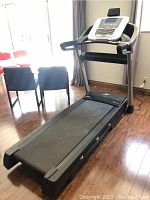 Full view of treadmill from front-left showing running deck and console