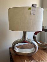 Side view of one table lamp showing metal open oval base and fabric drum shade with MaxSold tag