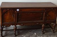 Front view of antique buffet showing three drawers and two side cabinets with detailed burled wood panels, standing on turned legs.