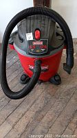Front view of a red and black Craftsman Shop-Vac wet/dry vacuum with flexible hose attached, showing model information and power switch.