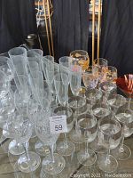 Overview of various clear crystal champagne flutes, decorated wine glasses with floral gold accents, and assorted glasses grouped together.