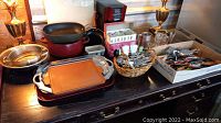 Overview of pots, pans, baking trays, silverware basket, and glasses on a dark wooden dresser.