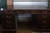 Front view of the vintage executive desk showing the nine drawers with brass handles and wood grain finish