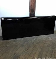 Full front view of the black king size headboard showing its rectangular shape and glossy finish.