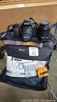 Nikon N70 camera, two lenses, Nikon case, manuals, and Kodak film box on table