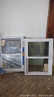 Pair of white framed replacement windows standing against a wall showing full view and design
