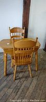 Photo showing small oak kitchen table with two pressed oak chairs in a room setting.
