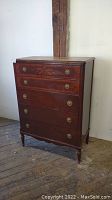Full view of tall antique 6 drawer wooden dresser with metal round pulls, showing its size and style.