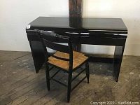 Front and side view of black vintage modern desk with chair, showing glossy finish and drawer fronts.