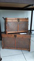 Two woven basket-style trunks stacked, showcasing the wood frame, woven wicker/basket panels, metal clasp closures, and side handles.