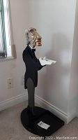 Full view of the tall butler statue figurine with hands extended holding a small white tray on a black oval base.
