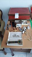 Photo showing the complete lot with jewelry box, necklaces, bracelets, pins, and brooches arranged on a table