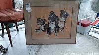 Full view of framed artwork showing three dogs and visible artist signature.