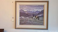 Full view of framed painting showing cowboy and two horses against mountain backdrop; wood frame and cream mat visible.