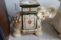 Full side view of ceramic elephant table/plant stand showing detailed carvings and painted accents