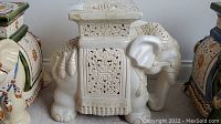 Full side view of white ceramic elephant-shaped table/plant stand with ornate decorations.