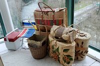 Photo of all items in the lot showing the folding chair, small cooler, and various straw totes and baskets with floral decorations and shell accents.