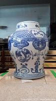 Front view of vase showing blue painted bird and decorative patterns on white ceramic body