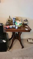 Front view of vintage wooden table with various decorative items on top and speaker nearby.
