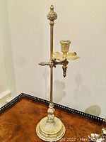 Full view of the antique adjustable candlestick showing the tall slender design with ornate base and candle cup.