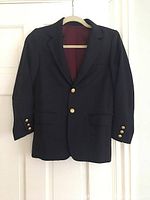 Front view of navy blue kids' blazer on hanger, showing gold buttons and front pockets.