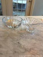 Two clear crystal items on marble table: large serving plate and smaller decorative bowl