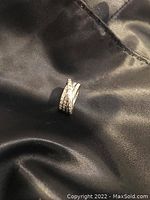 Ring front view on black fabric background showing intertwined bands and diamond pavé