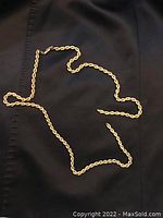 Entire rope chain laid out on fabric background showing overall condition and broken clasp
