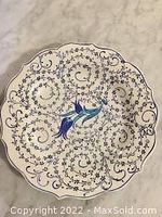 Full view of the round handmade Turkish ceramic art plate featuring intricate blue floral and swirl patterns on white.