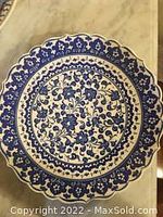 Full view of the handmade Turkish art plate showing intricate blue floral designs and scalloped edges on white ceramic.