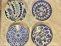 Top view of four different Turkish handmade ceramic plates displaying varied floral and geometric blue patterns.